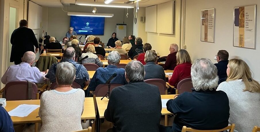 Ett avlångt konferensrum fullt med folk.