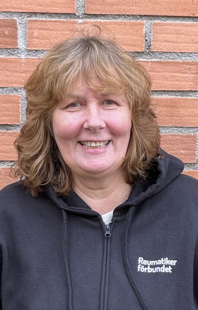 Victoria Jern Nilsson, Lokalvårdare Marie har brunt lockigt hår och en svart munkjacka med Reumatikerförbundets logotyp på bröstet.